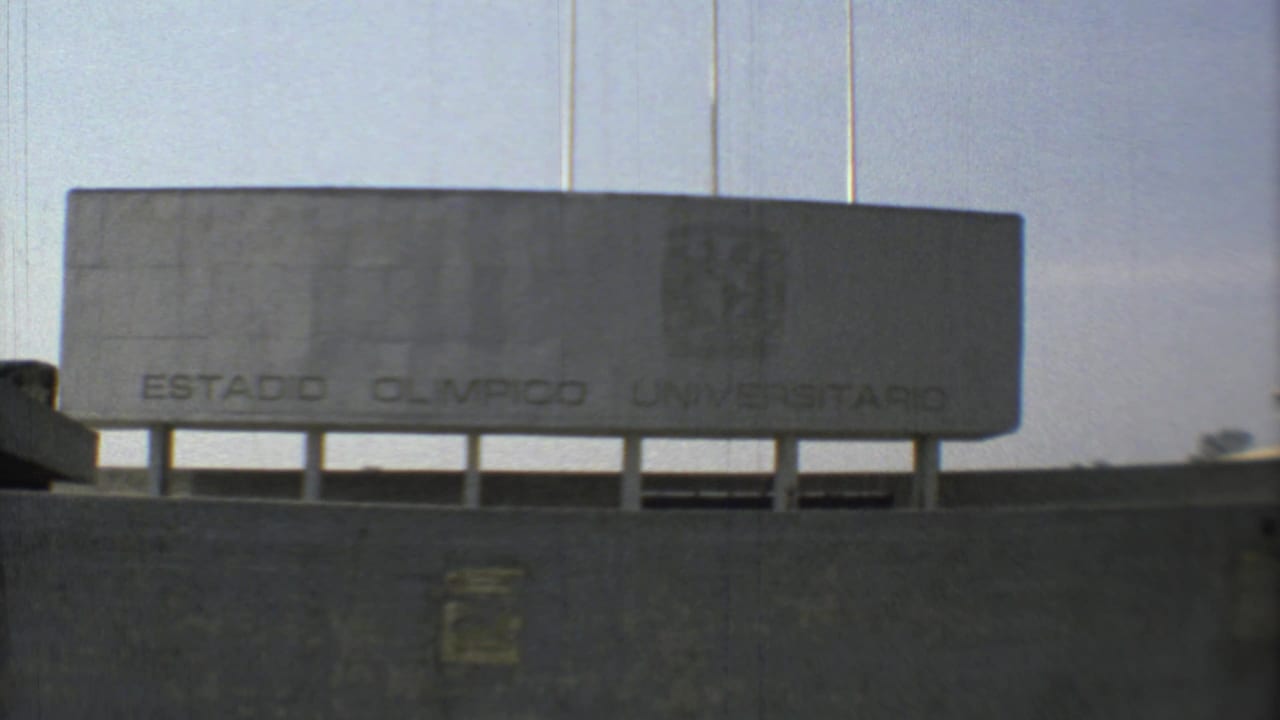 1973 Mexico City frame centered on the Estadio Olimpico Universitario sign mounted above a concrete stadium wall.