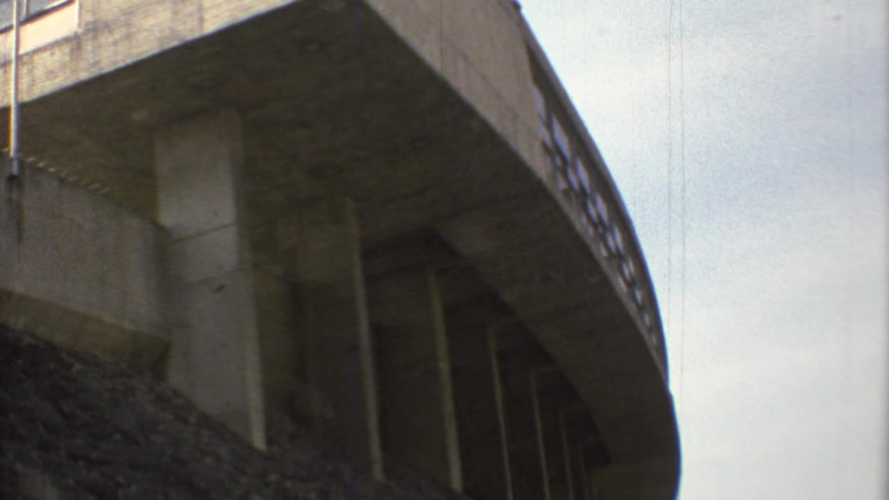 Low-angle view beneath a concrete overpass with support pillars and a sloped embankment.