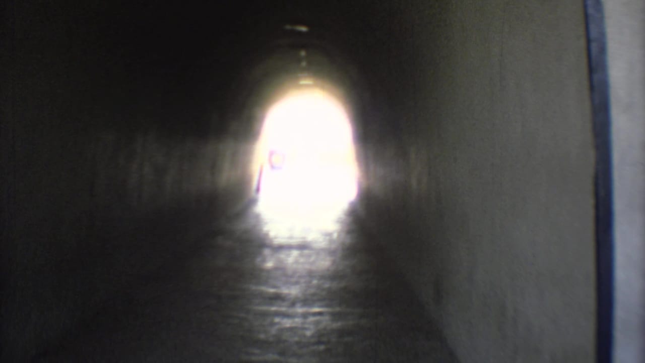1973 Mexico City 8mm frame looking through a dark underpass toward a bright exit from a moving vehicle.