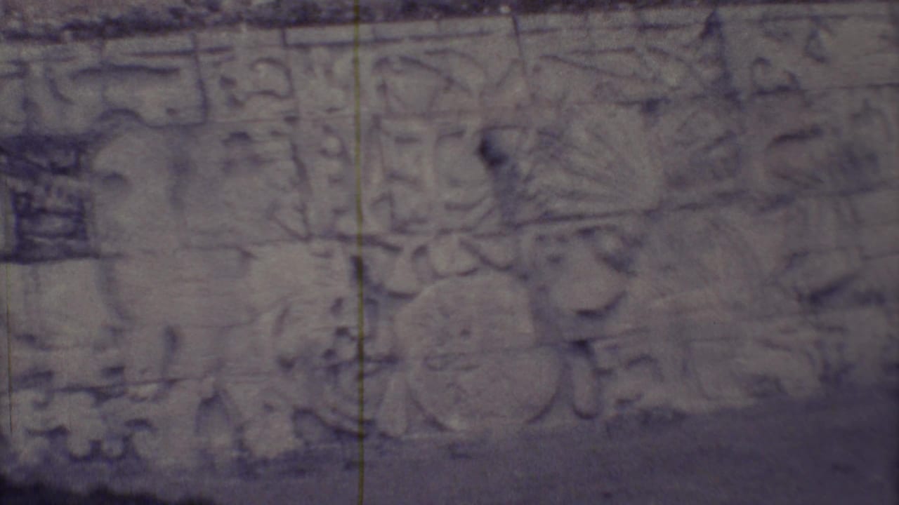 1973 Yucatan 8mm close-up of weathered Maya-style carved stone glyphs and relief forms on a wall surface.