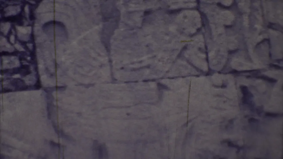 1973 Yucatan close-up showing worn carved stone panels, glyph-like marks, and relief figures in grainy 8mm footage.