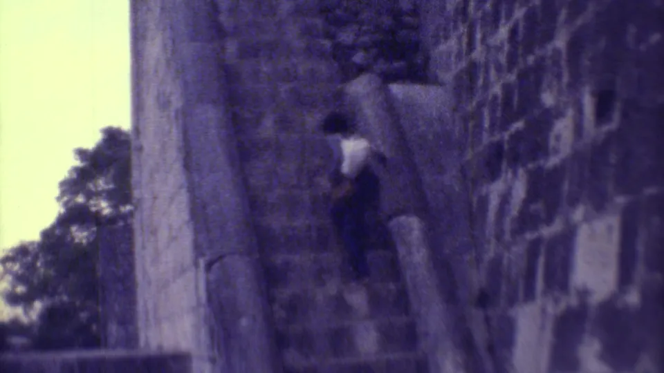 A woman climbs steep stone steps beside a massive weathered wall at a Yucatan ruin site in 1973.