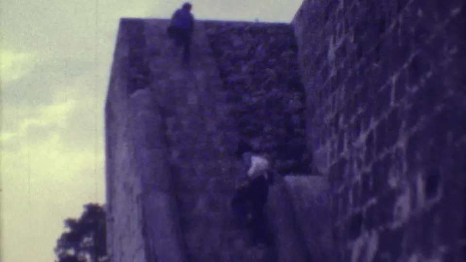 One visitor stands near the top of the ruin while another climbs the stairway below in 1973 Yucatan home-movie footage.