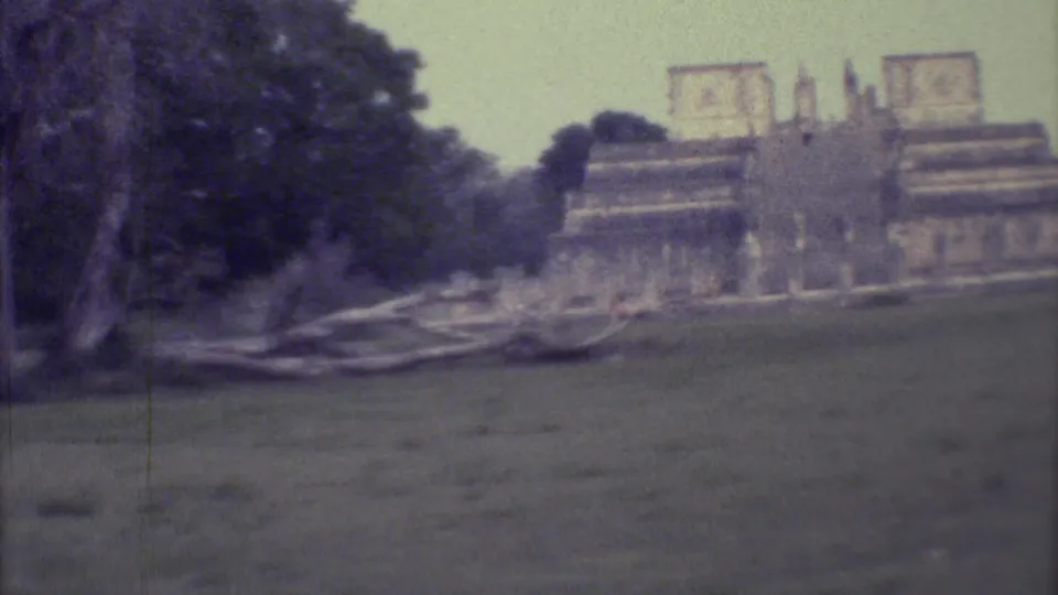A visitor-shot 1973 Yucatan frame shows trees and low stone remains leading toward a tan stepped monument.