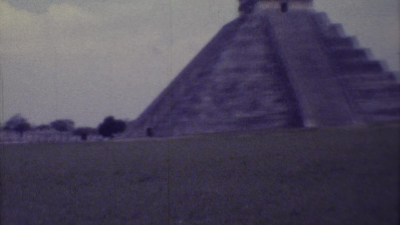 Soft 8mm view of El Castillo pyramid behind a grassy foreground.