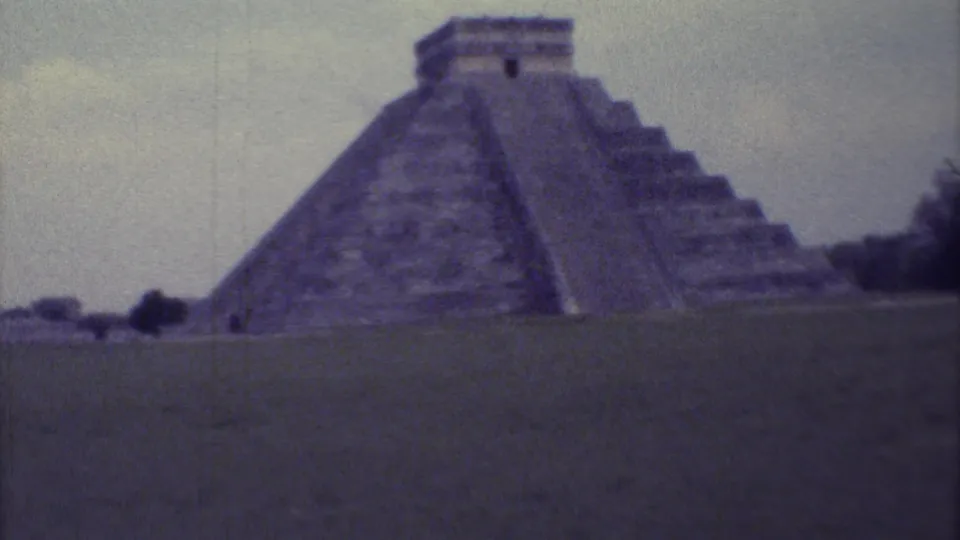 El Castillo at Chichen Itza appears in a soft, grainy 1973 8mm frame with trees along the edge of the site.