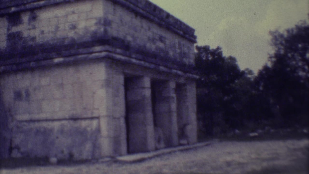 1973 8mm Yucatan footage showing a weathered Mayan stone structure with columned openings and tropical trees behind it.