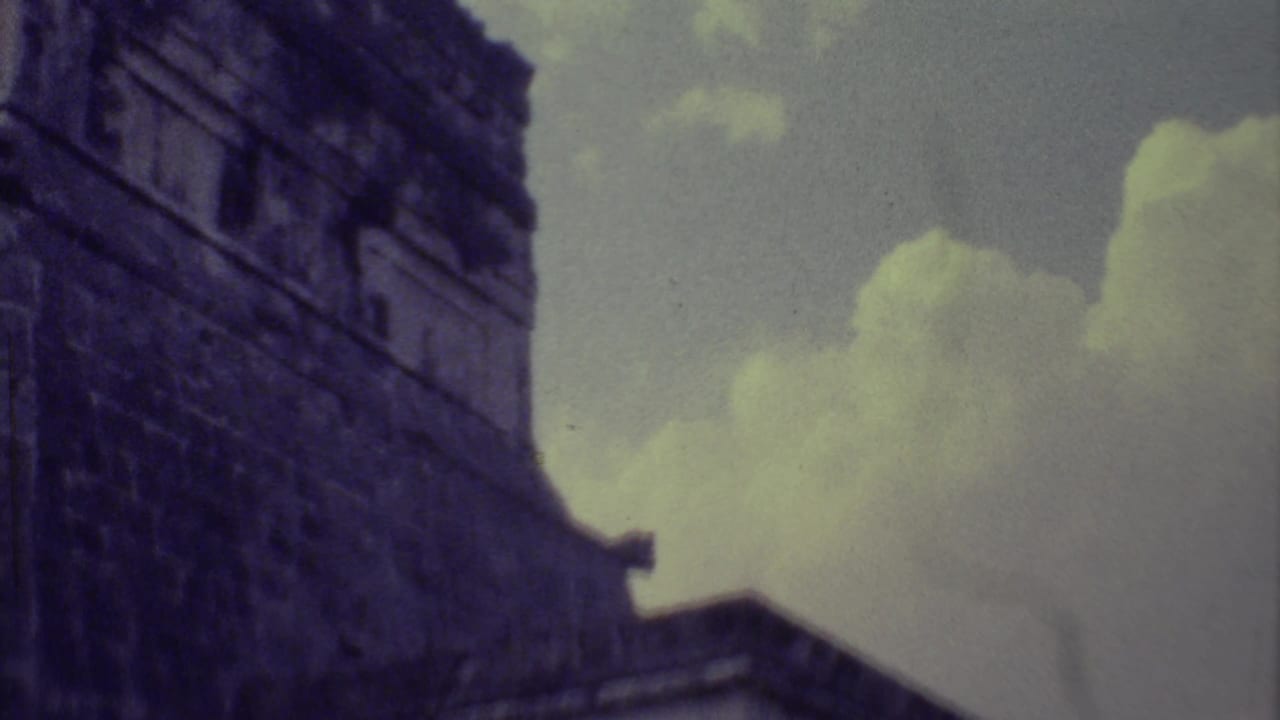 Dark stone ruin wall seen from below against a cloudy sky.
