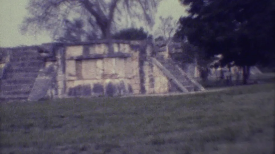 1973 Yucatan 8mm frame showing a closer view of weathered stonework, stair edges, grass, and surrounding trees.