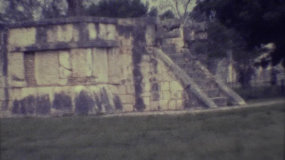 1973 Yucatan 8mm frame showing a weathered stone structure with a steep stairway, grass in front, and dense trees behind.