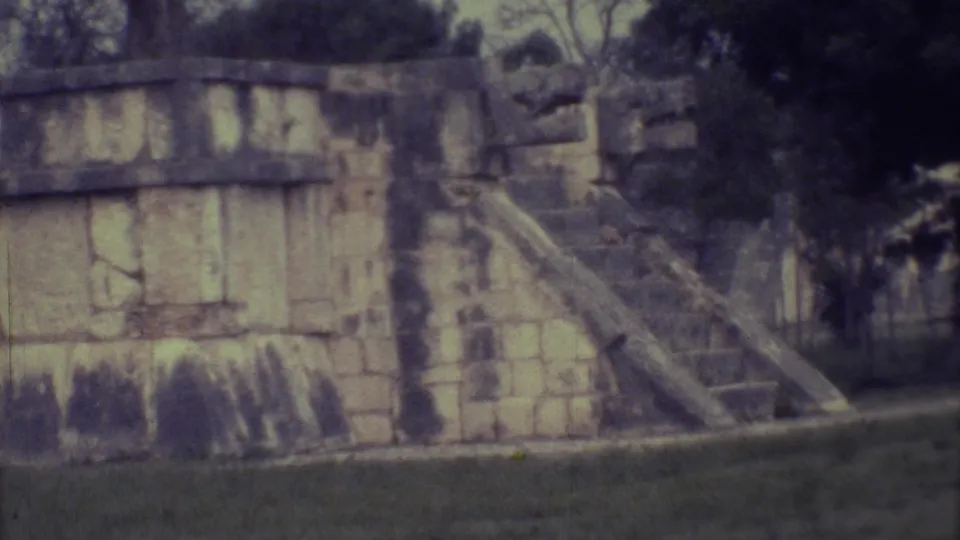1973 Yucatan 8mm view of a block-like stone structure and angled stairway bordered by grass and tropical foliage.