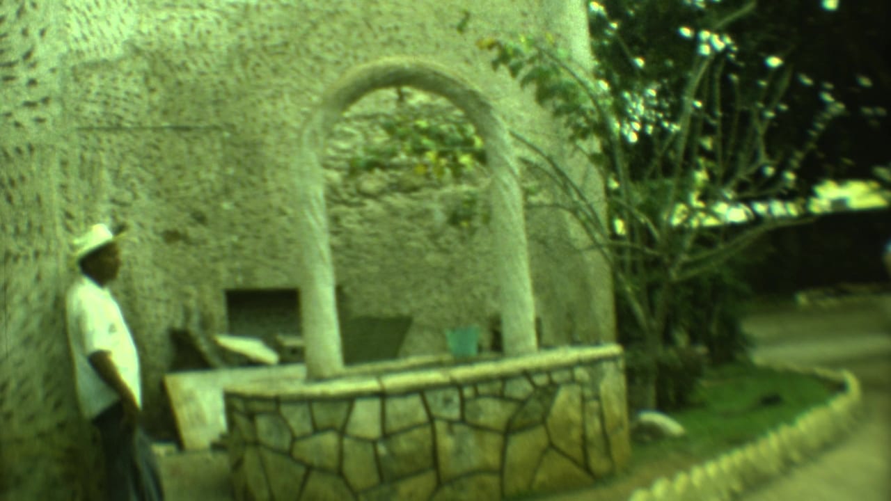 1973 Yucatan 8mm frame showing a man beside a weathered stone well or arched structure in a shaded tropical setting.