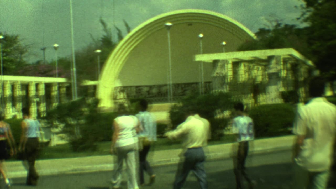 Pedestrians continue along a path near matching curved dome structures and garden planting.