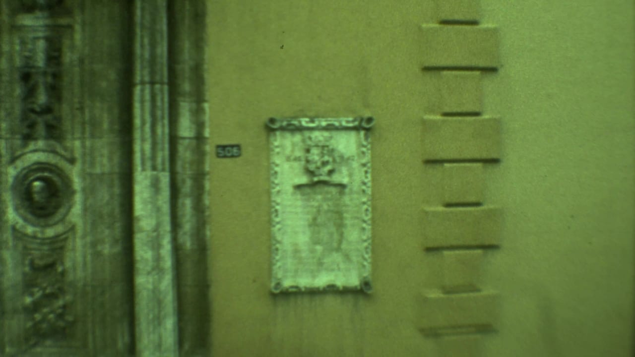 Close view of a stucco wall with a weathered plaque and ornate stone doorway details.