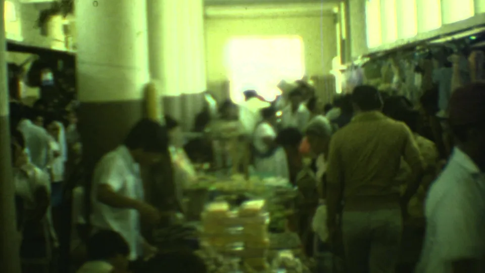1973 Yucatan 8mm frame showing a crowded indoor market with adults browsing goods under bright interior light.