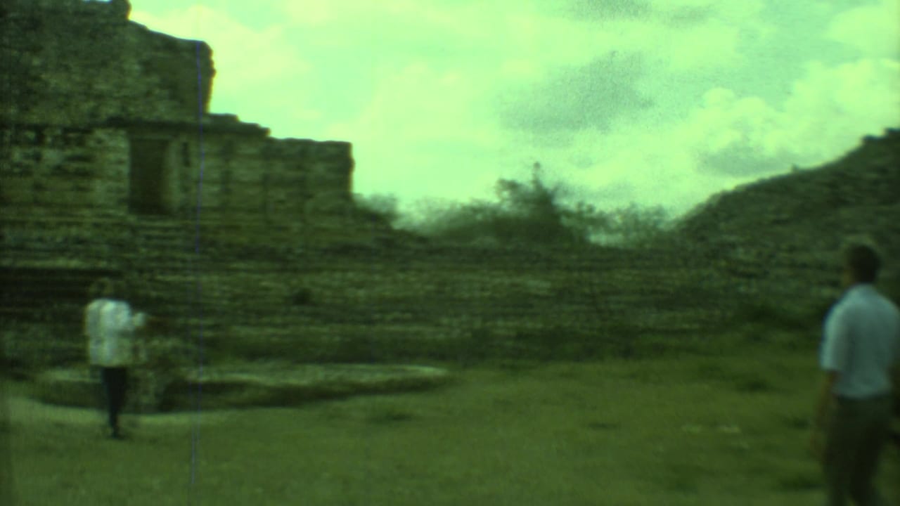 Stone building with dark openings as people stand and walk nearby.