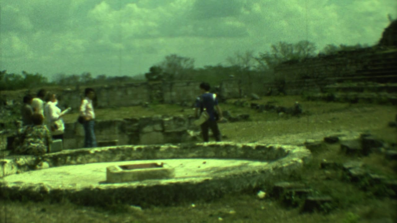 Tourists walk among stone ruins under a cloudy sky.