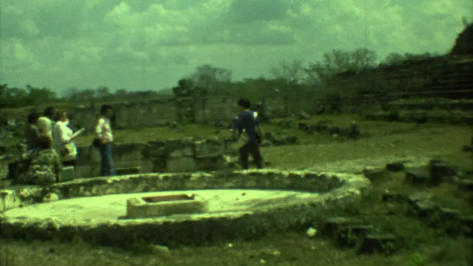 Tourists explore a Yucatan archaeological ruin in 1973, with low stonework and stepped masonry in view.