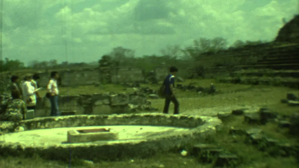 A 1973 Yucatan tourist scene shows a man in blue walking near ancient stone remains and a visitor group.