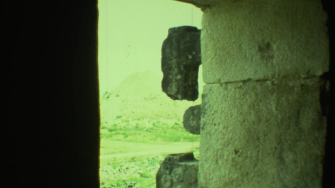 Shadowed doorway and rough stone blocks with bright exterior ground beyond.