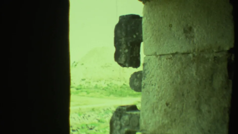 1973 Yucatan home-movie frame showing a close, obstructed view of rough stonework and a bright archaeological exterior.