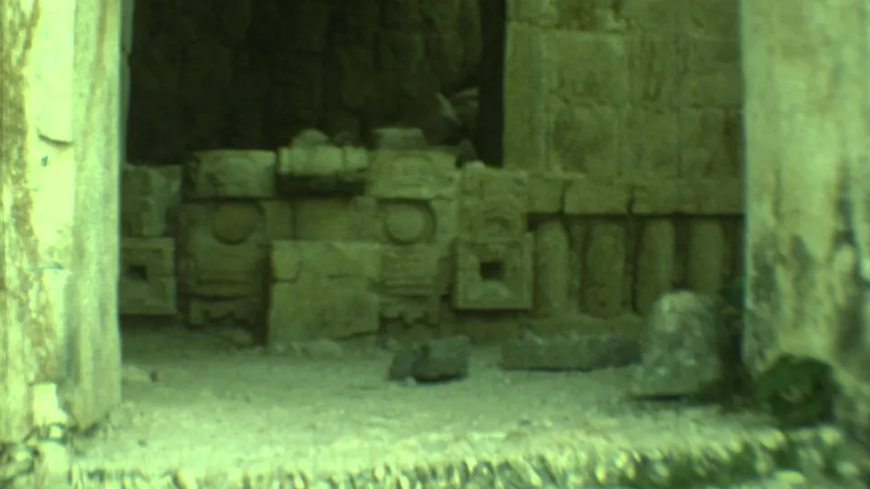 A 1973 Yucatan 8mm frame shows stacked carved stone blocks and columns within a shadowed archaeological structure.