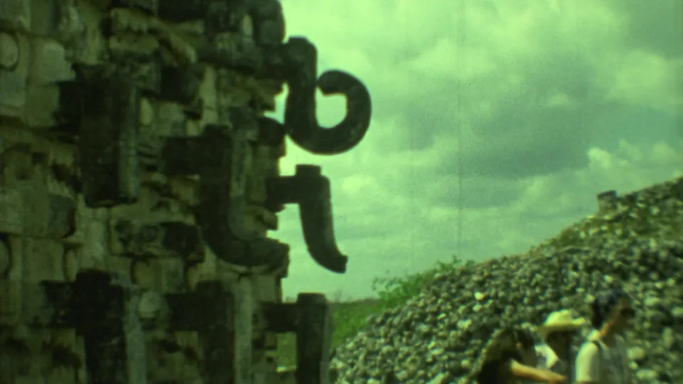 A close view of carved ruin details frames tourists walking near a Yucatan archaeological site in 1973 8mm footage.