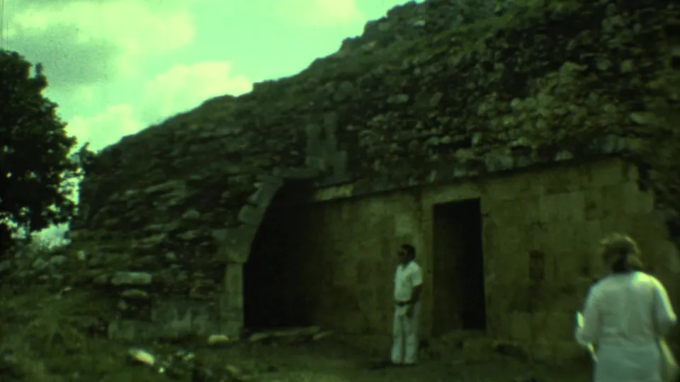 Tourists stand near an arched ruin and dark doorway at a historic site in Yucatan, Mexico, captured on 1973 8mm film.