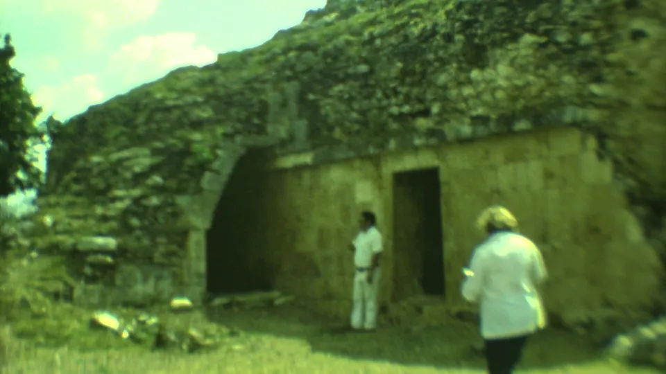 At a Yucatan ruin in 1973, visitors stand near an arched opening while one person appears to photograph the structure.