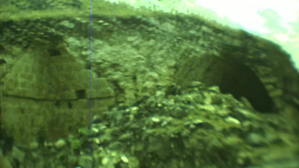 1973 Yucatan frame showing rough stone ruins and a dark cave-like entrance, with no people prominent in view.
