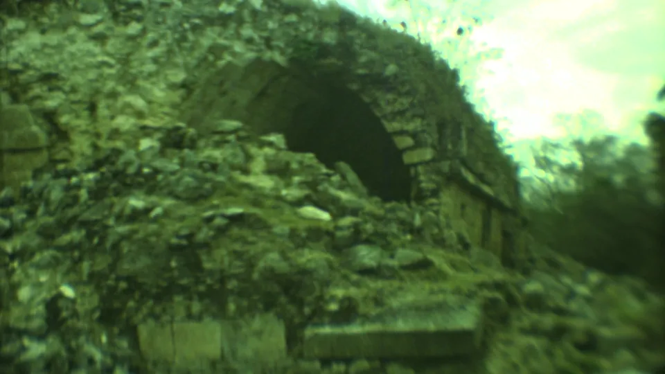 1973 Yucatan home-movie frame of a large arched ruin partly obscured by rubble and soft focus.
