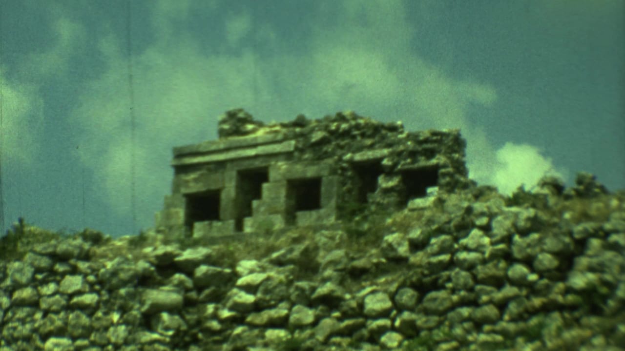 Closer view of a weathered stone building above a rough wall and rocks.
