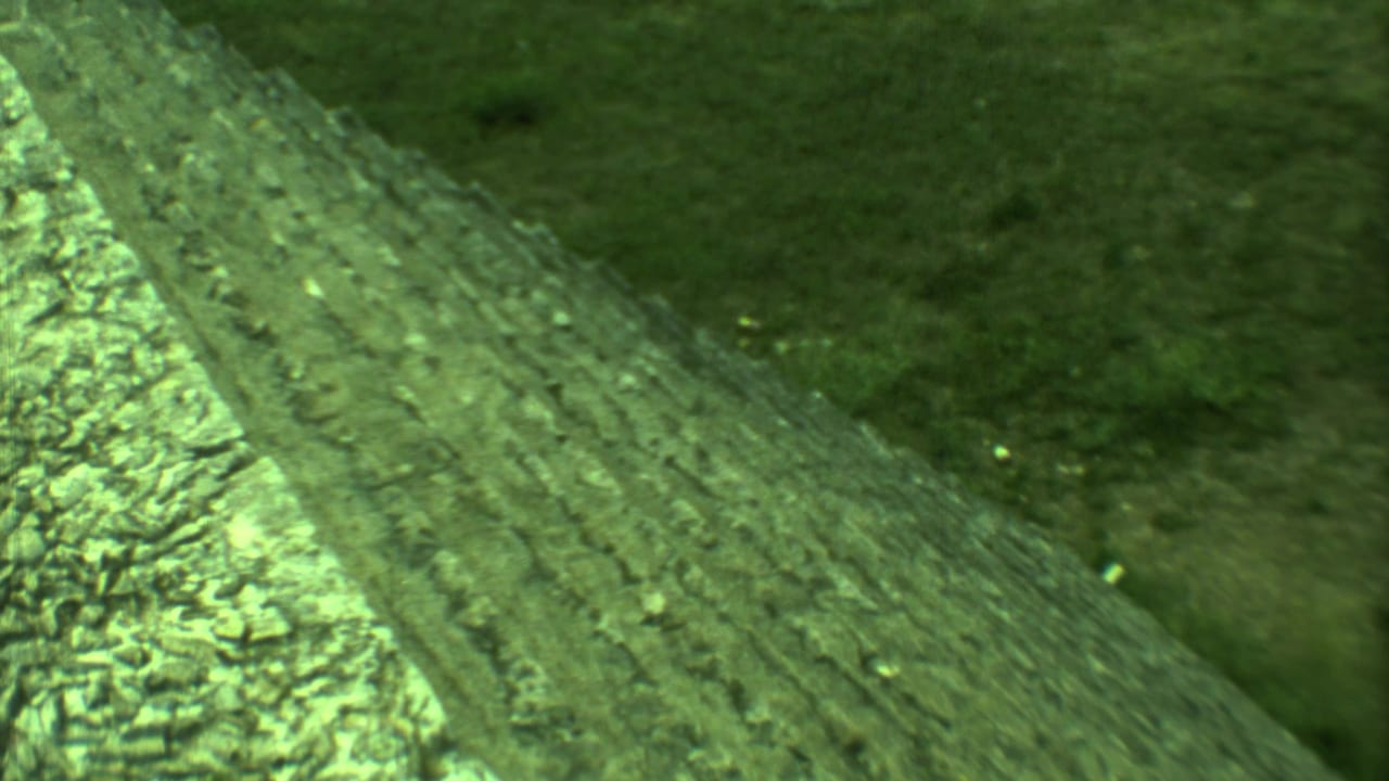 Green-tinted close view of steep weathered stone steps and grassy ground.