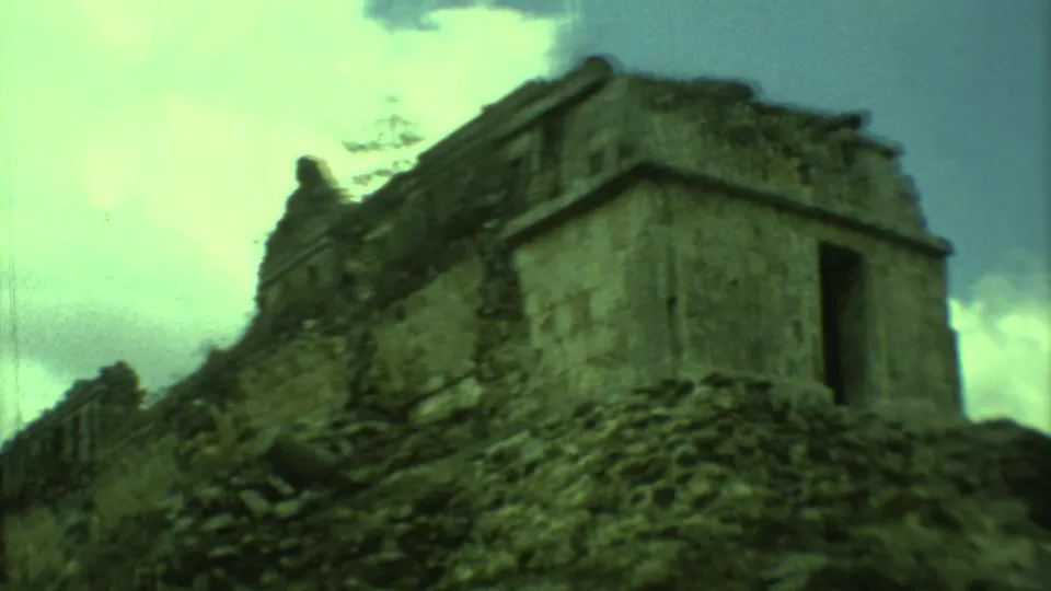 1973 Yucatan 8mm frame showing a closer low-angle view of a weathered Mayan ruin with doorway and rubble slope.