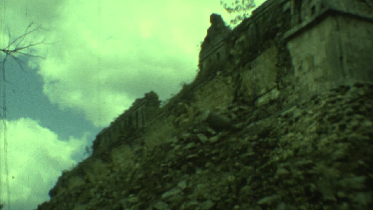 Low-angle view of a crumbling stone wall and rubble slope under cloudy sky.