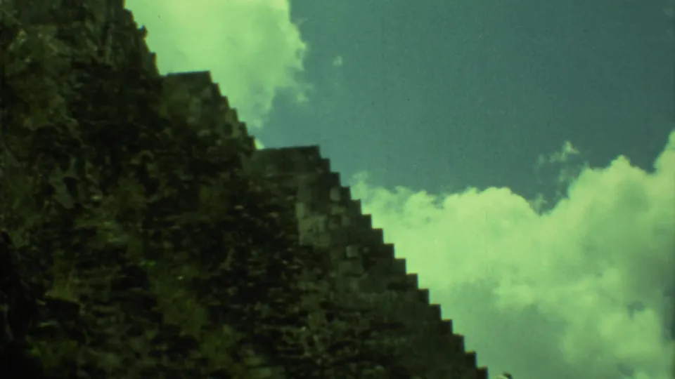 Green-shifted 8mm frame of the Yucatan pyramid's stepped stone profile with clouds behind it.