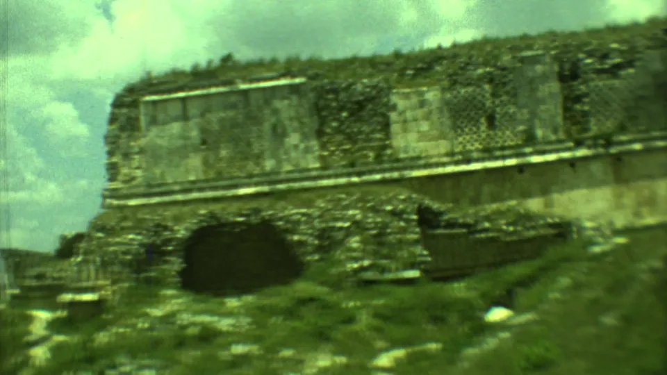 1973 Yucatan 8mm frame showing a weathered stone ruin, dark doorway-like opening, and grass below.