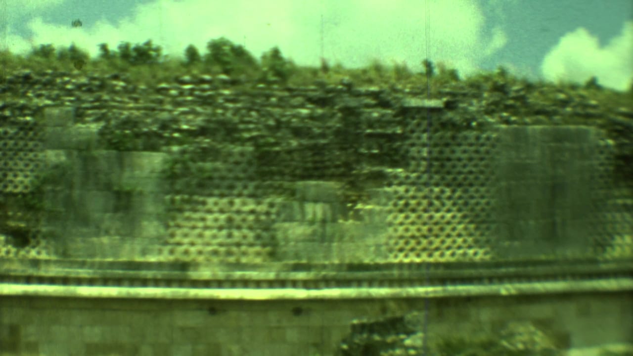 Weathered stone ruin with lattice-pattern wall and bright clouds above.