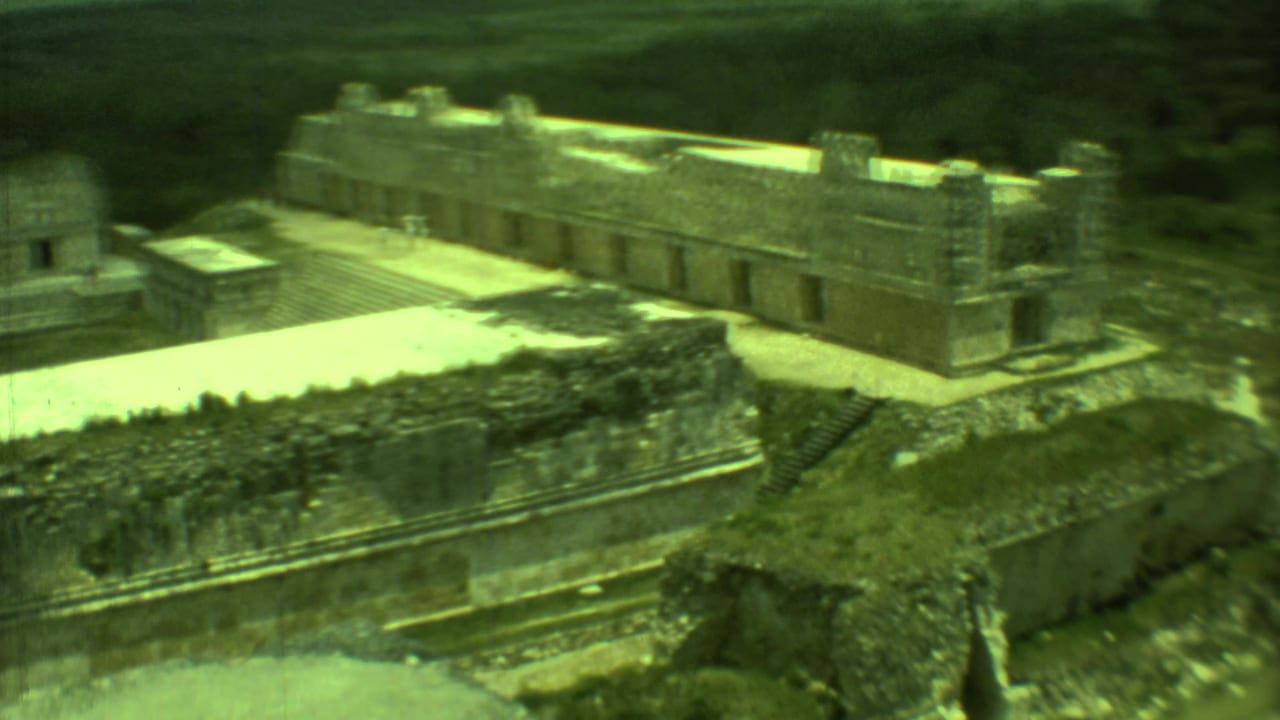 Elevated view of weathered stone ruins, pale walkways, and green countryside.