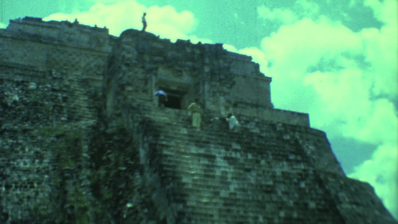 1973 Yucatan home-movie view of tourists standing and climbing on a weathered stone pyramid.