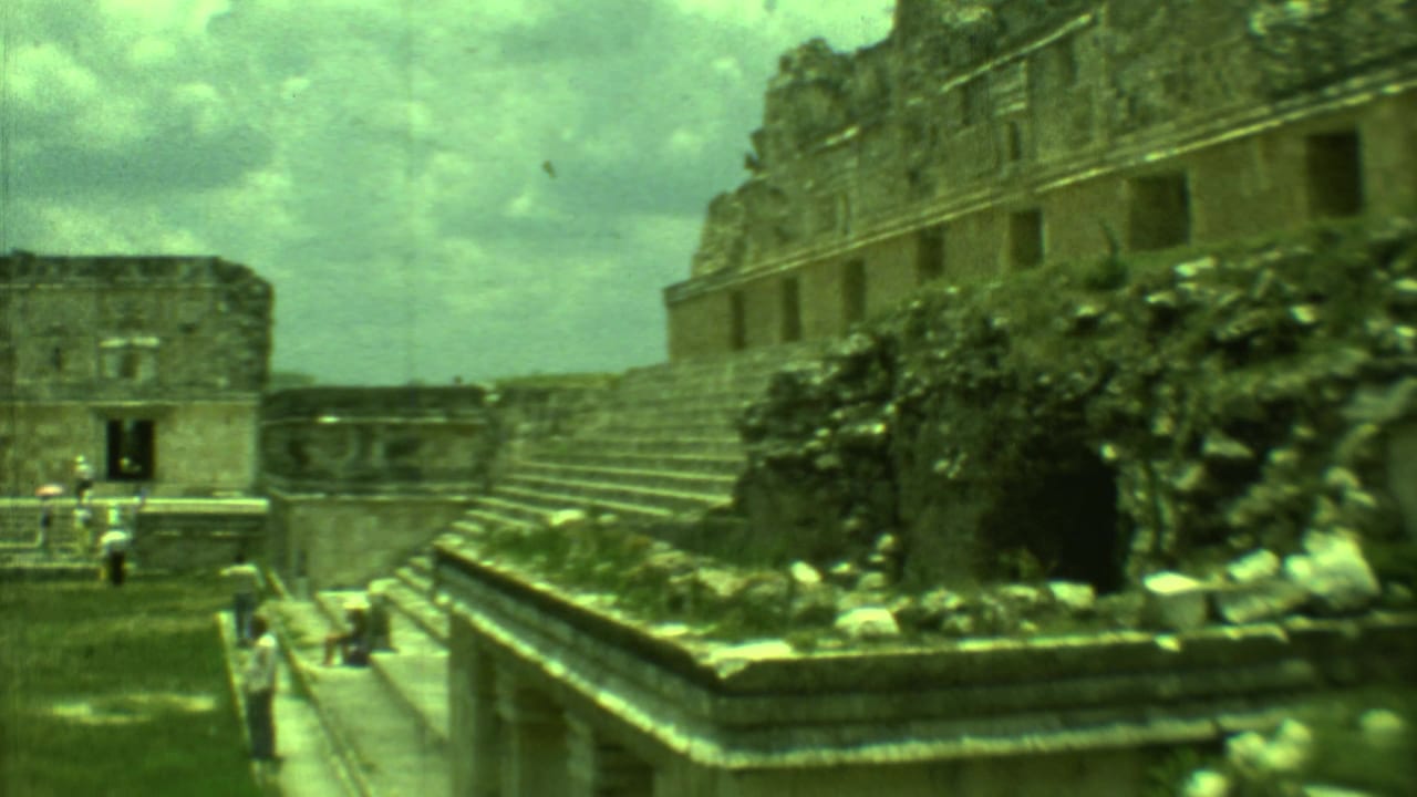 Tourists near stone stairways and platforms at an ancient ruin site under cloudy sky.