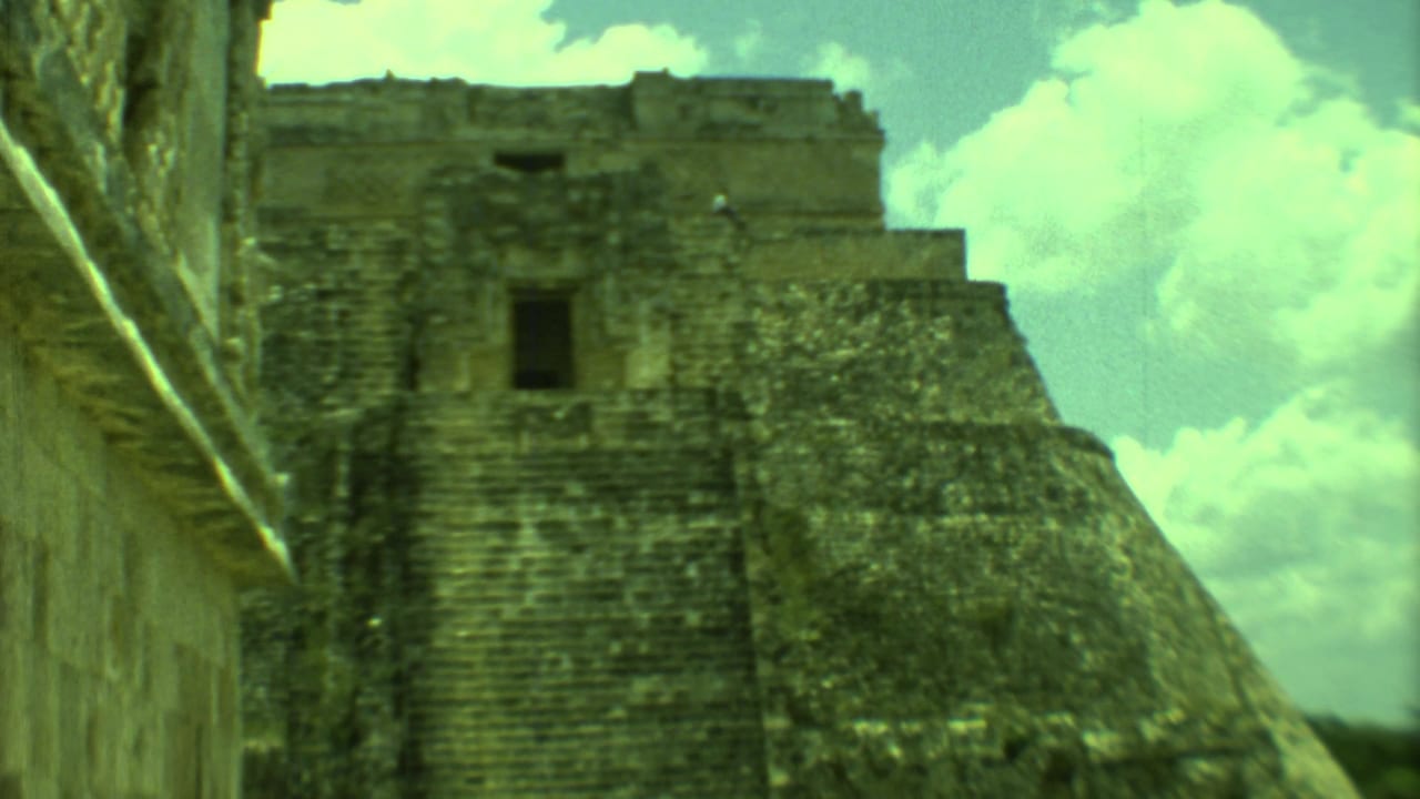 1973 Yucatan travel footage frame with a close view of the pyramid face, upper platform, and bright clouds.