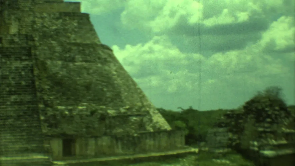 1973 Yucatan frame showing the pyramid slope with greenery and a smaller structure in the distance.