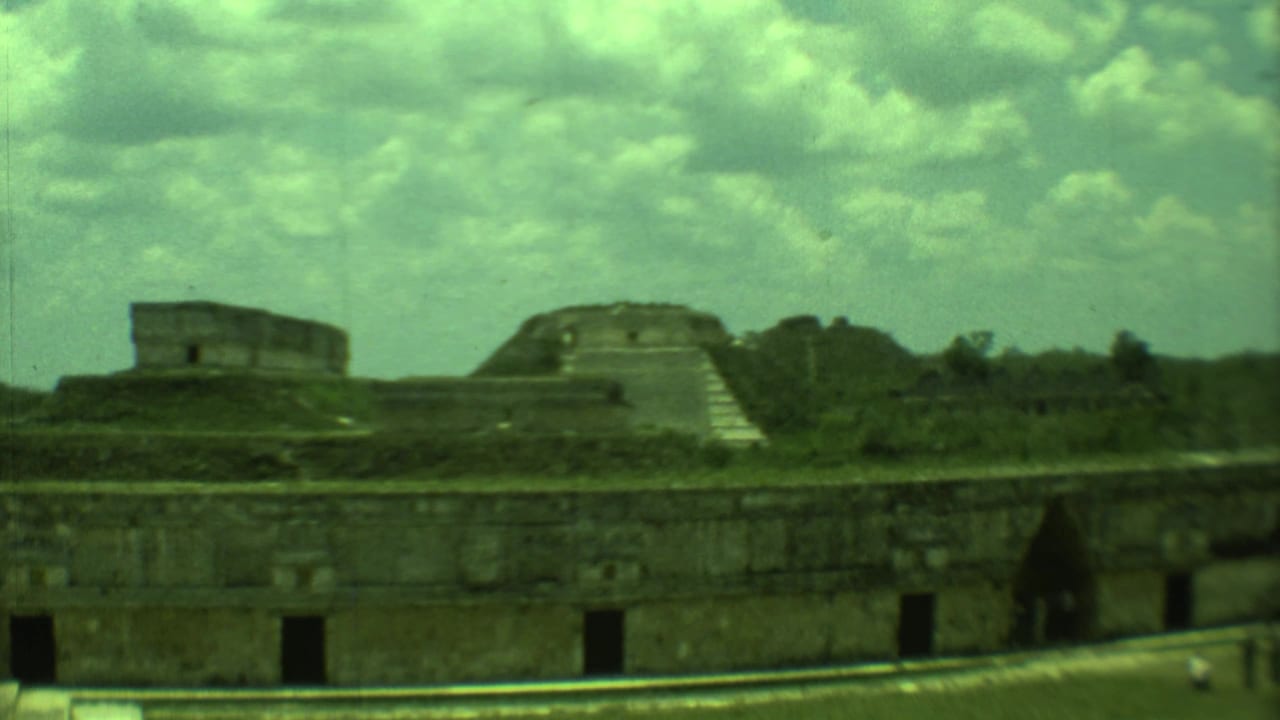 Stone platform and pyramid-like ruin seen across grassy grounds.