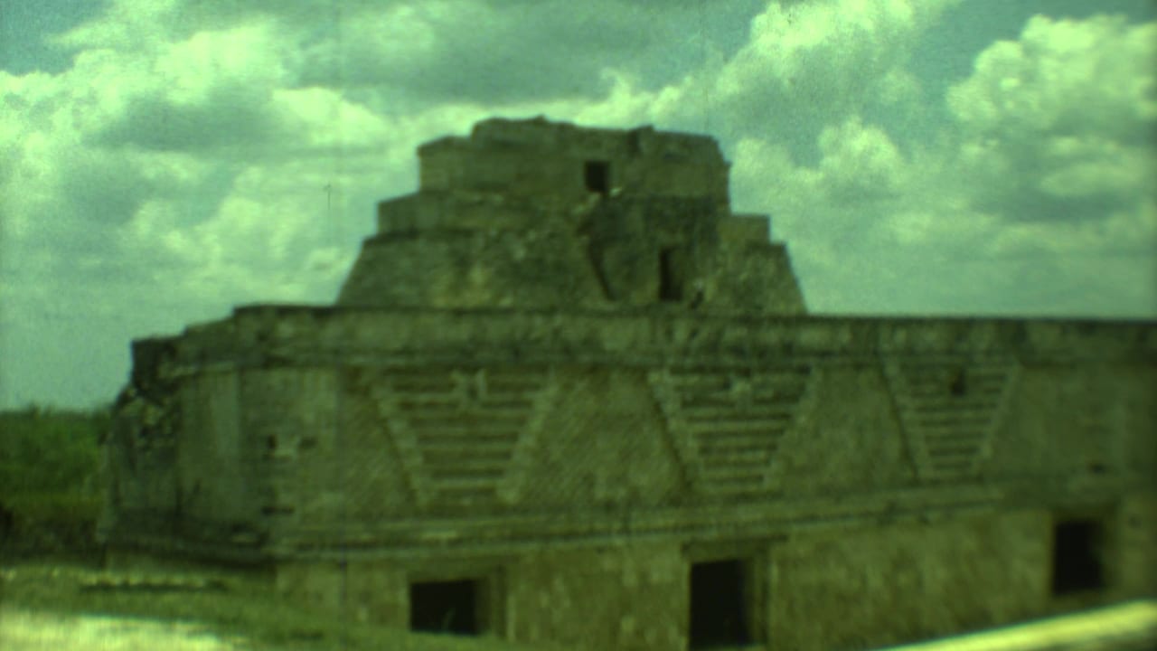 Stepped stone ruin with triangular facade patterns below a cloudy sky.