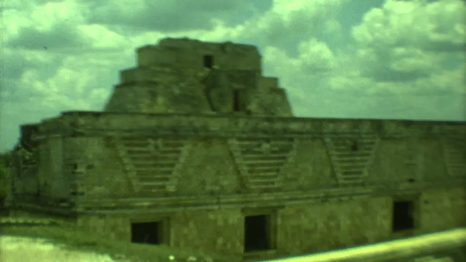 1973 Yucatan 8mm frame showing a large stepped stone ruin, dark doorways, and a cloudy midday sky.