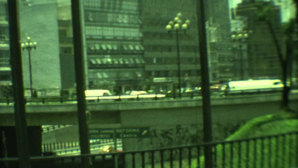 1973 Yucatan, Mexico urban overpass scene with cars, globe streetlamps, foreground railings, trees, and modern building facades.