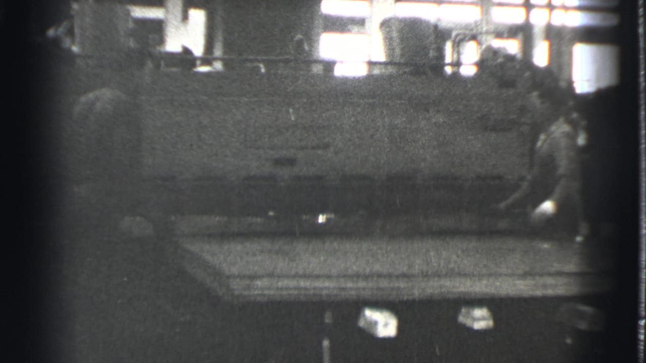 A worker stands at the right side of a large machine with a flat panel in front.