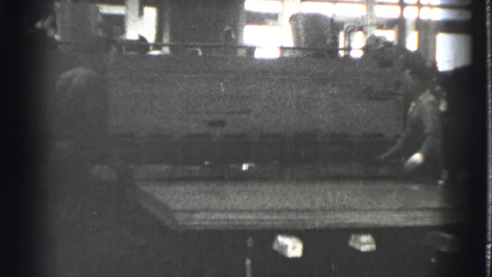 A worker appears beside heavy machinery and a broad flat panel in a 1939 Cleveland industrial interior.
