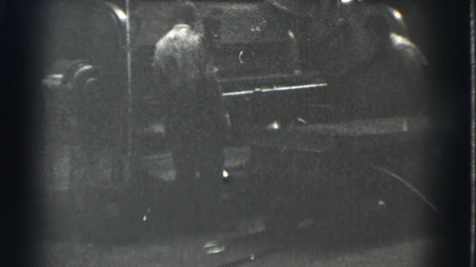 Two adult men are visible beside machinery in the grainy black-and-white 1939 Cleveland industrial home movie.
